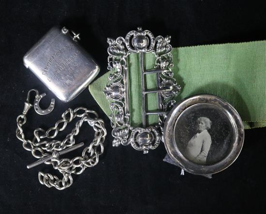 An Edwardian silver nurses buckle, a silver vesta, a silver albert and a silver photograph frame.